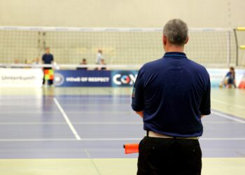 Kapalı salonda voleybol sahasına arkası dönük duran hakem.