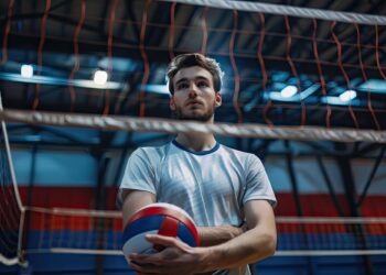 Salonda file önünde elinde voleybol topu tutan sporcu.
