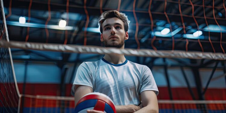 Salonda file önünde elinde voleybol topu tutan sporcu.