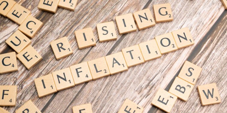 Ahşap Scrabble harfleriyle oluşturulmuş 'Rising Inflation' yazısı ve etraftaki harfler.