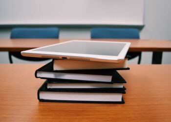 Ahşap masa üzerinde duran kitaplar ve üstünde dijital tablet.