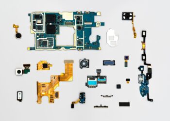 Sökülmüş akıllı telefon parçaları ve elektronik devre kartları düz zeminde sergileniyor.