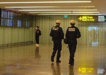 Havalimanı koridorunda devriye gezen üniformalı iki polis memuru.