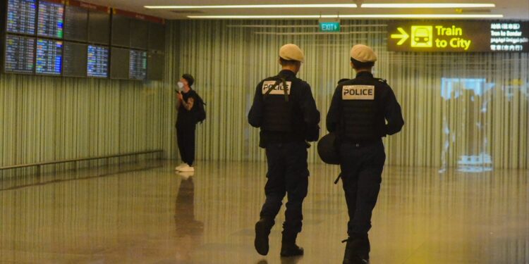 Havalimanı koridorunda devriye gezen üniformalı iki polis memuru.