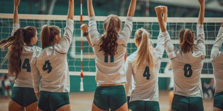 Arkaları dönük, ellerini havaya kaldırarak sevinç yaşayan kadın voleybol takımı.