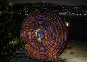 Gece vakti İstanbul silüeti önünde renkli ışıklı dairesel sanat enstalasyonu.
