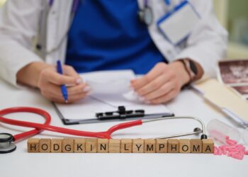 Masada stetoskop ve reçete bulunan doktorun önündeki ahşap harflerle Hodgkin Lymphoma yazıyor.