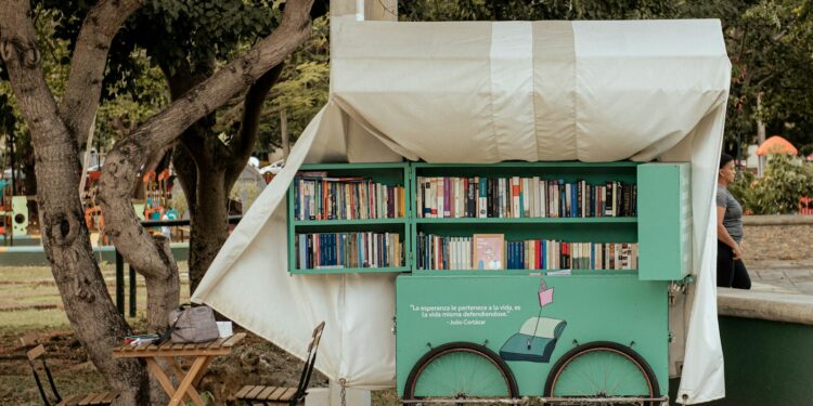 Ağacın altında kitaplarla dolu tezgahın bulunduğu açık hava kitap fuarı.