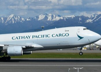 Kalkış yapan Cathay Pacific kargo uçağı ve arkasında karlı dağlar.