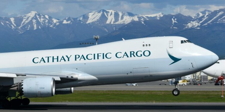 Kalkış yapan Cathay Pacific kargo uçağı ve arkasında karlı dağlar.