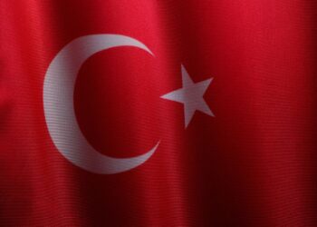 Kırmızı zemin üzerinde dalgalanan Türk bayrağı ve beyaz ay yıldız detayları.