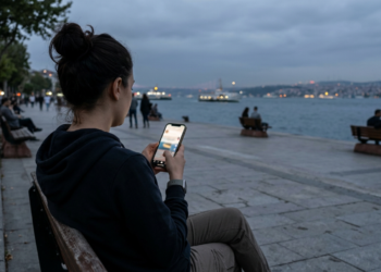 Boğaz manzaralı bir bankta oturup telefonuyla ilgilenen genç kadın.