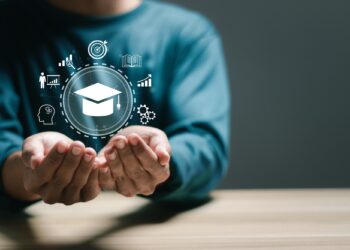 Eğitim ve vizyon simgeleriyle dolu dijital bir küreyi ellerinde tutan kişi.