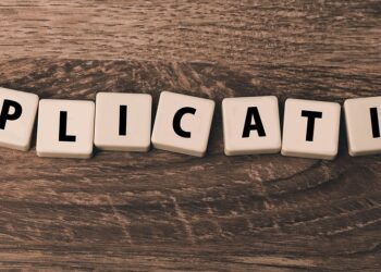 Ahşap masa üzerinde harf küplerinden oluşan İngilizce application kelimesi.