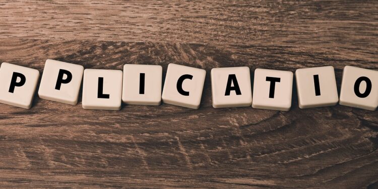Ahşap masa üzerinde harf küplerinden oluşan İngilizce application kelimesi.