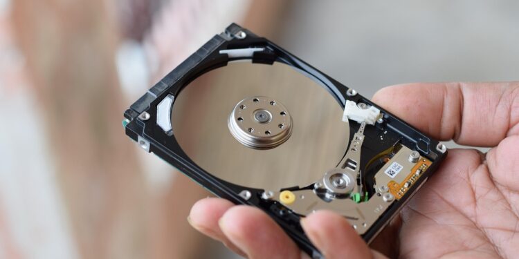 Elde tutulan açık bir sabit disk ve mekanik bileşenleri.